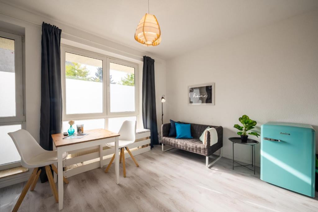 a living room with a table and a blue refrigerator at Moderne EG-Wohnung in Sudenburg mit Parkplatz, TOP Anbindung in Magdeburg