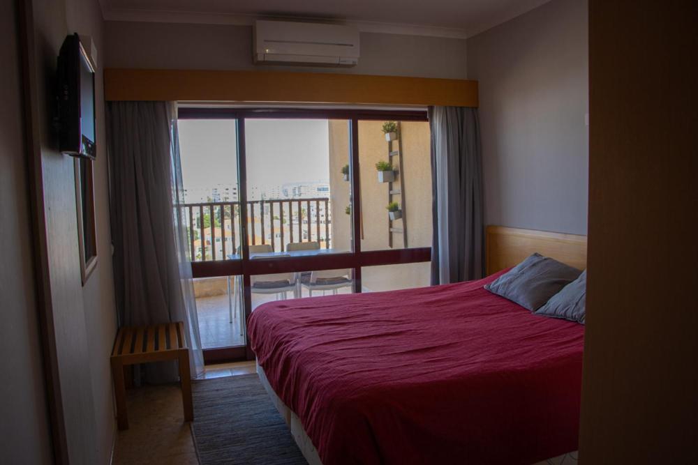 una camera con letto rosso e balcone di ApartPatos Luxury Home a Portimão