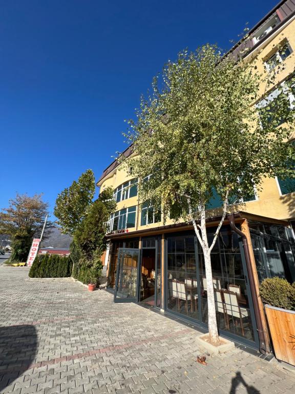 un edificio con un árbol delante de él en Hotel Yal Restaurant, en Tetovo
