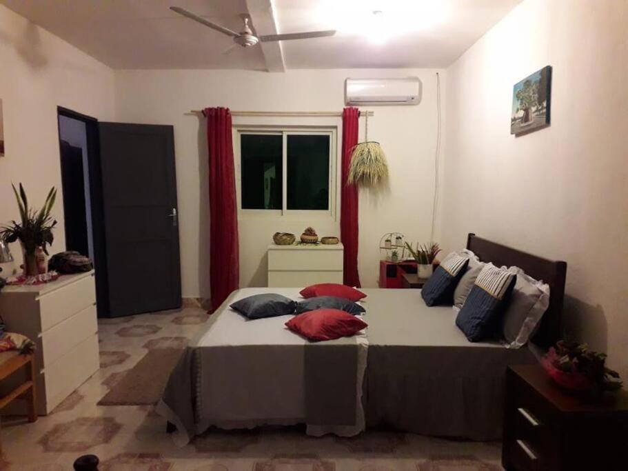 Un dormitorio con una cama con almohadas rojas. en Appartement à 2 pas de l'ilôt de Sada., en Sada