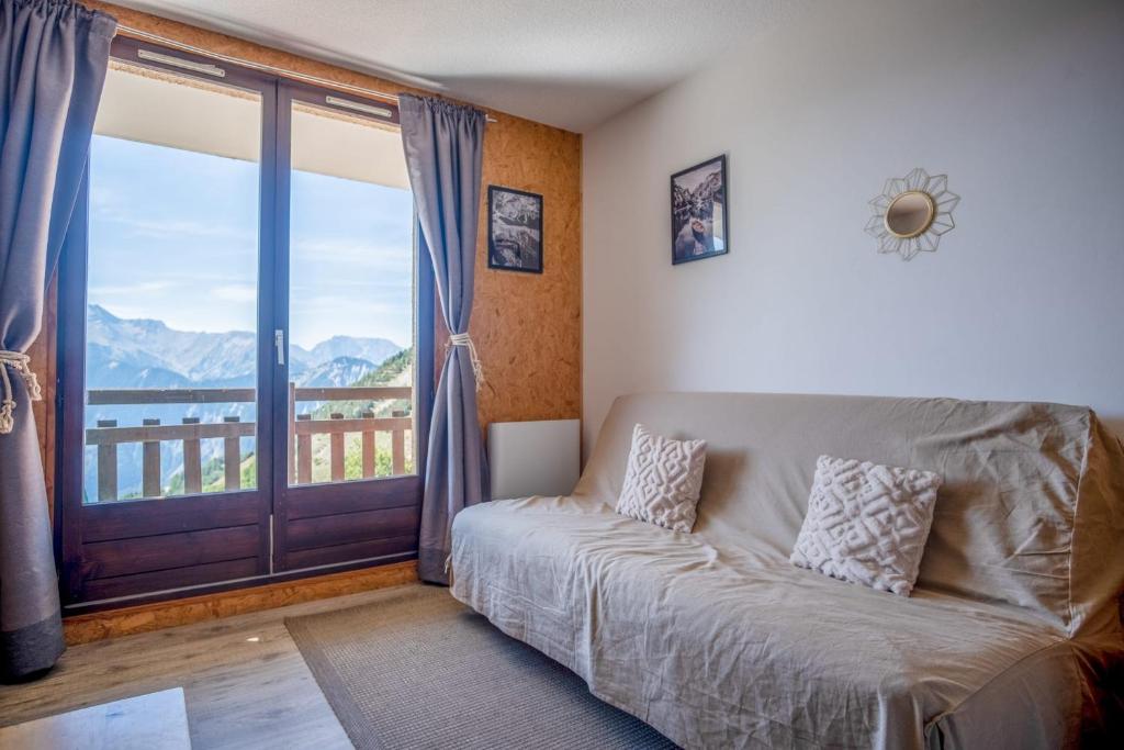 sala de estar con sofá y ventana grande en Studio with balcony and beautiful view - Alpe d'Huez - Welkeys en LʼHuez