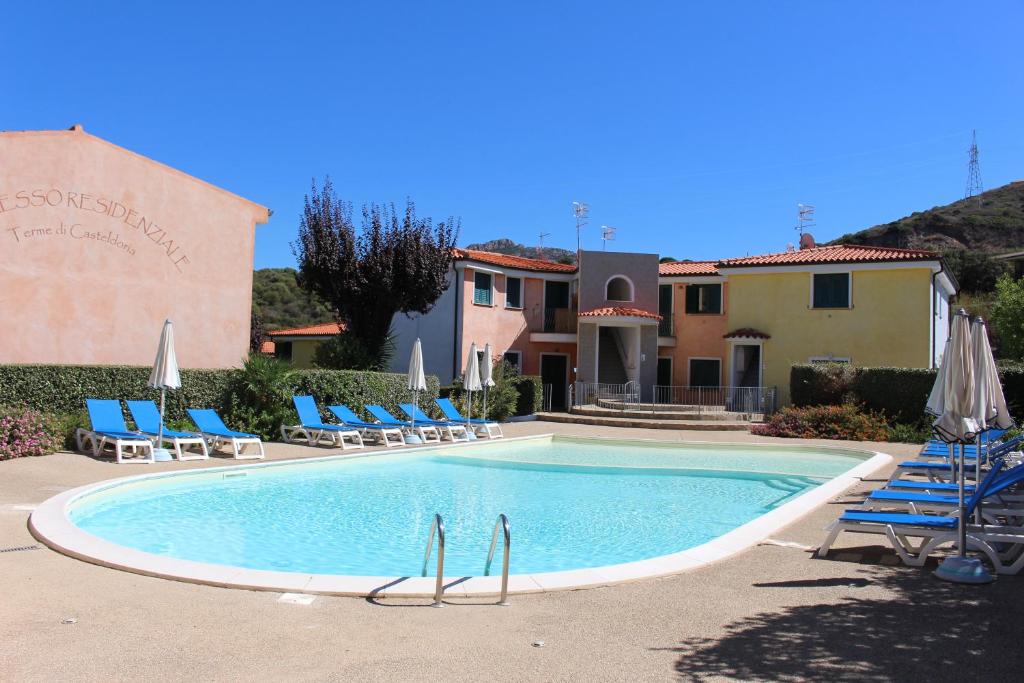 basen z leżakami i parasolami obok domu w obiekcie Appartamento 38 - Complesso Residenziale Terme di Casteldoria w mieście Santa Maria