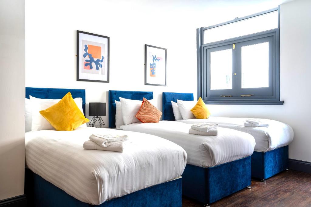 two beds in a room with blue and yellow pillows at The Cavern Quarter Aparthotel by UStay in Liverpool