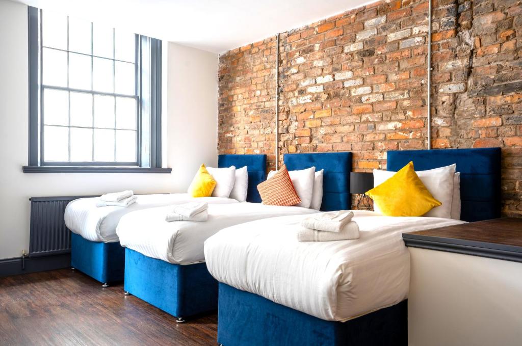 two beds in a room with a brick wall at The Cavern Quarter Aparthotel by UStay in Liverpool
