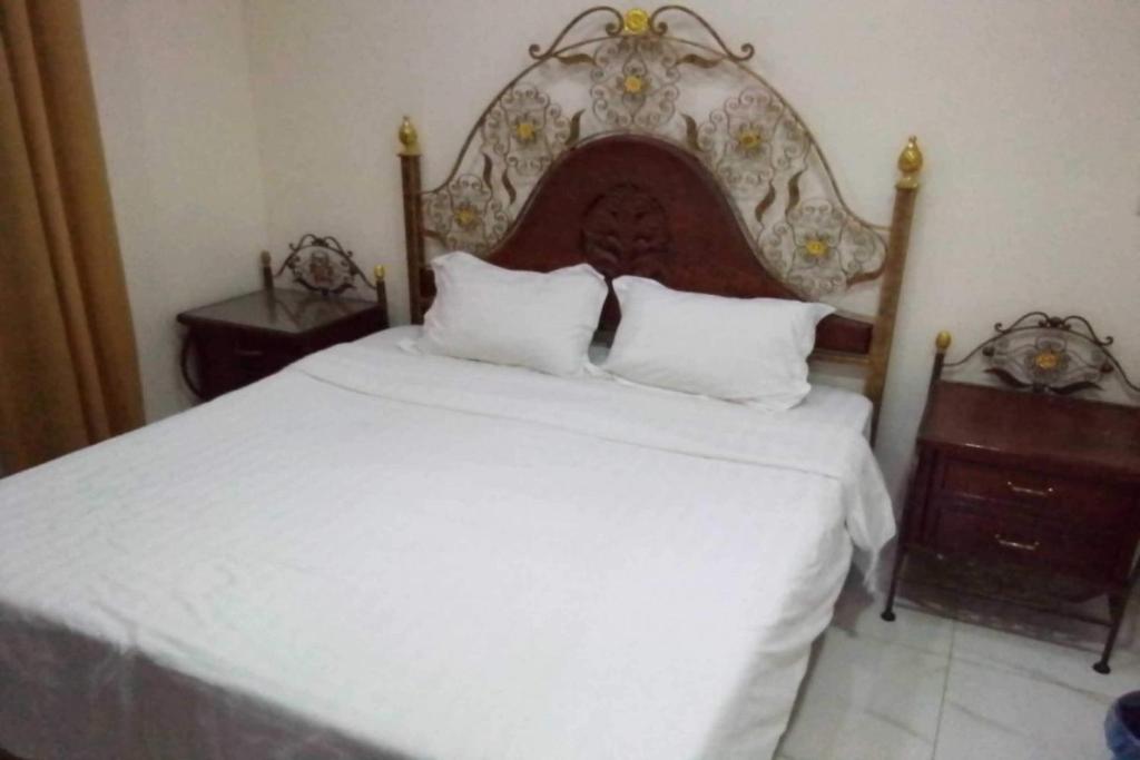 a bedroom with a white bed with a large headboard at OYO 639 Home Furnished Apartments - 2BHK in Al Khobar