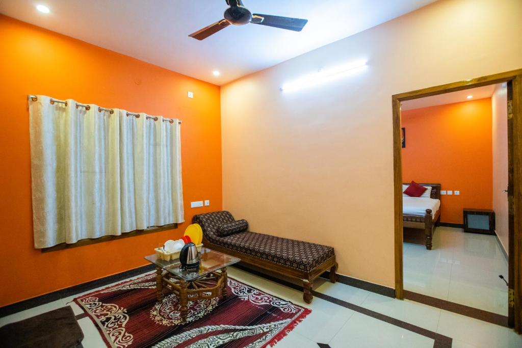 a living room with orange walls and a couch and a mirror at Sri Balaji Villas in Puducherry