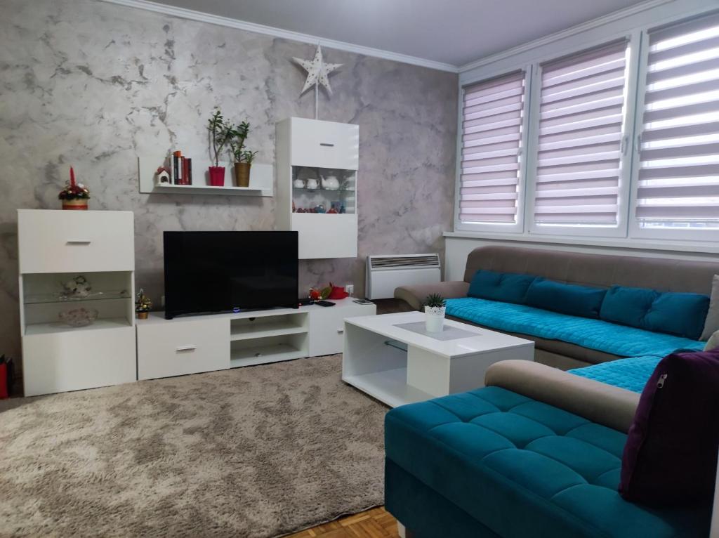 sala de estar con sofá azul y TV en Agape apartman en Višegrad