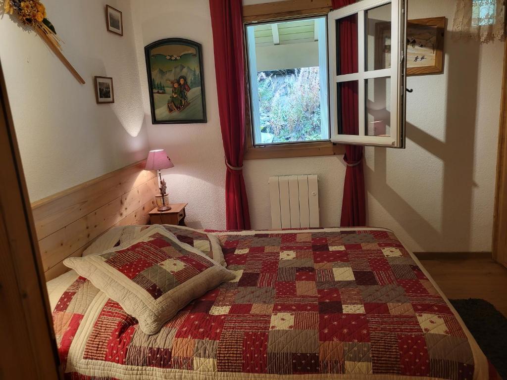 a bedroom with a bed with a quilt and a window at MAGNIFIQUE APPARTEMENT AVEC TERRASSE et VUE IMPRENABLE SUR LE CIRQUE DE FLAINE, 2 chambres et coin montagne, 6 personnes in Flaine