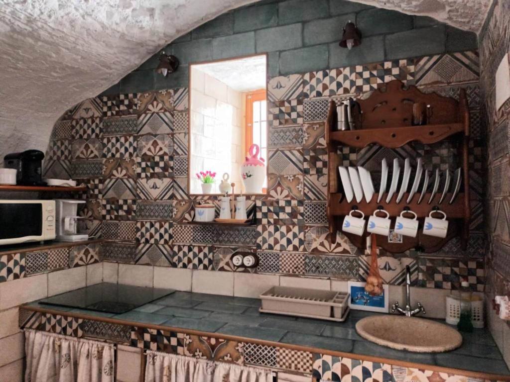 eine Küche mit einem Waschbecken und einer gefliesten Wand in der Unterkunft Cuevas Baza in Baza