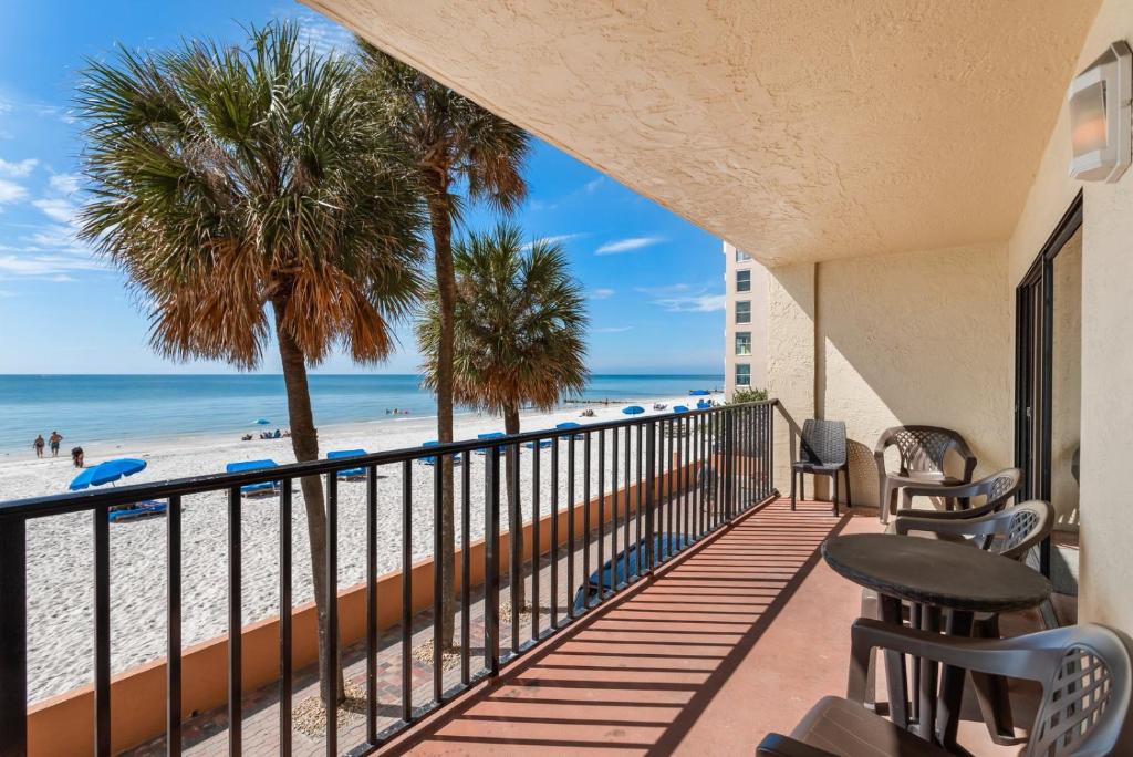 a balcony with a view of the beach and palm trees at 104 Las Brisas Condo in St Pete Beach