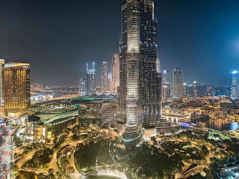 una vista de la ciudad por la noche con un edificio alto en Magnificent 2 BR with Stunning Burj Khalifa View, en Dubái