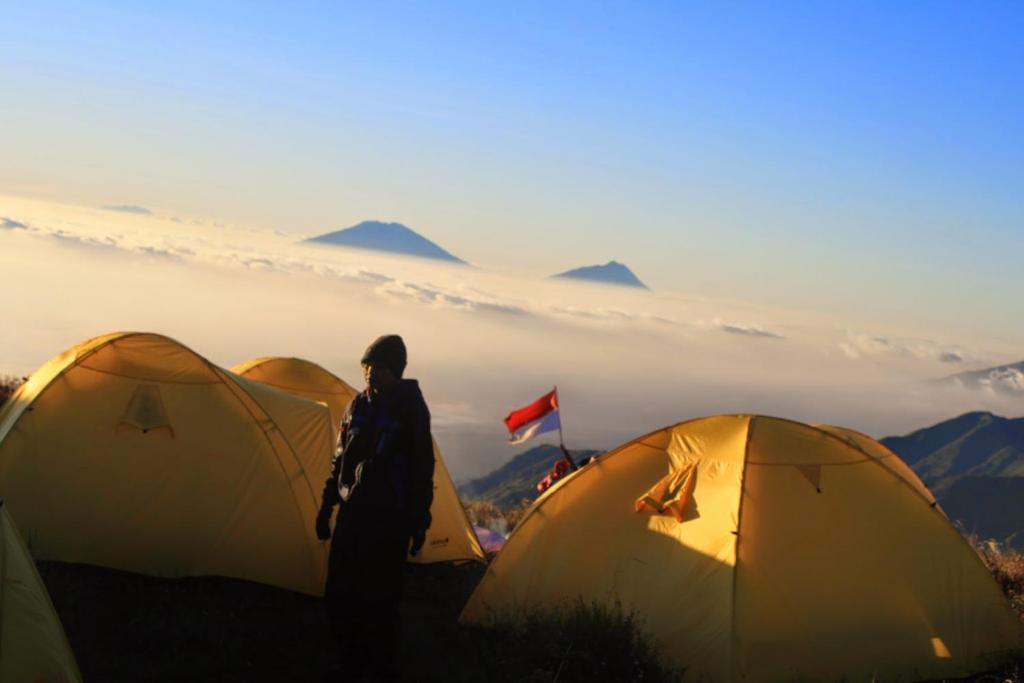 Baturaja的住宿－Batur Sunset Sunrise camping，站在三个帐篷前的人