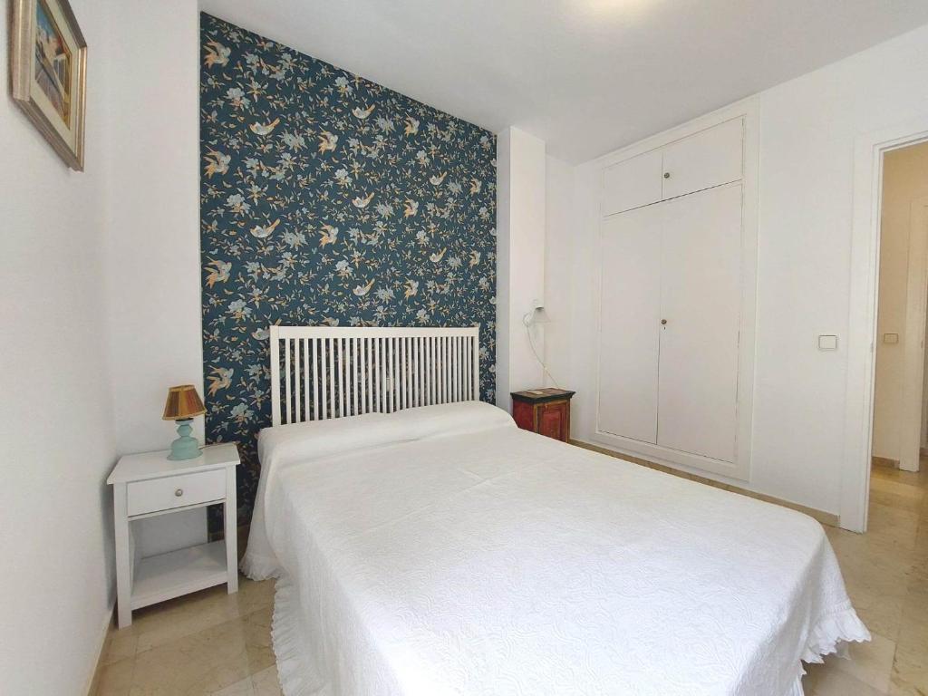 een slaapkamer met een wit bed en een bloemaccentmuur bij Carlos Cañal in Sevilla