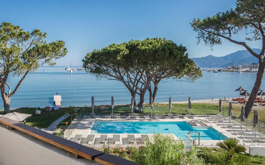 - une piscine avec des chaises et une vue sur l'eau dans l'établissement Hôtel La Roya, à Saint-Florent