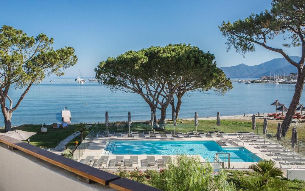 a swimming pool with chairs and a view of the water at Hôtel La Roya in Saint-Florent