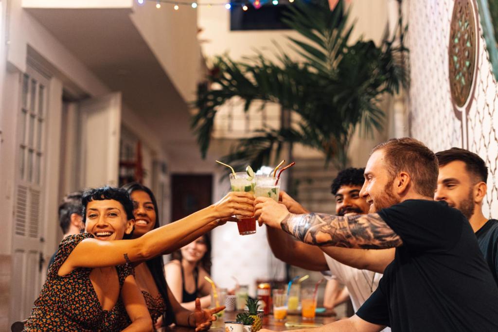 un grupo de personas sentadas en una mesa sosteniendo una bebida en Discovery Hostel, en Río de Janeiro