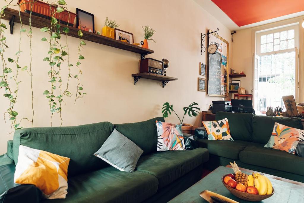 a living room with a green couch with a bowl of fruit at Discovery Hostel in Rio de Janeiro
