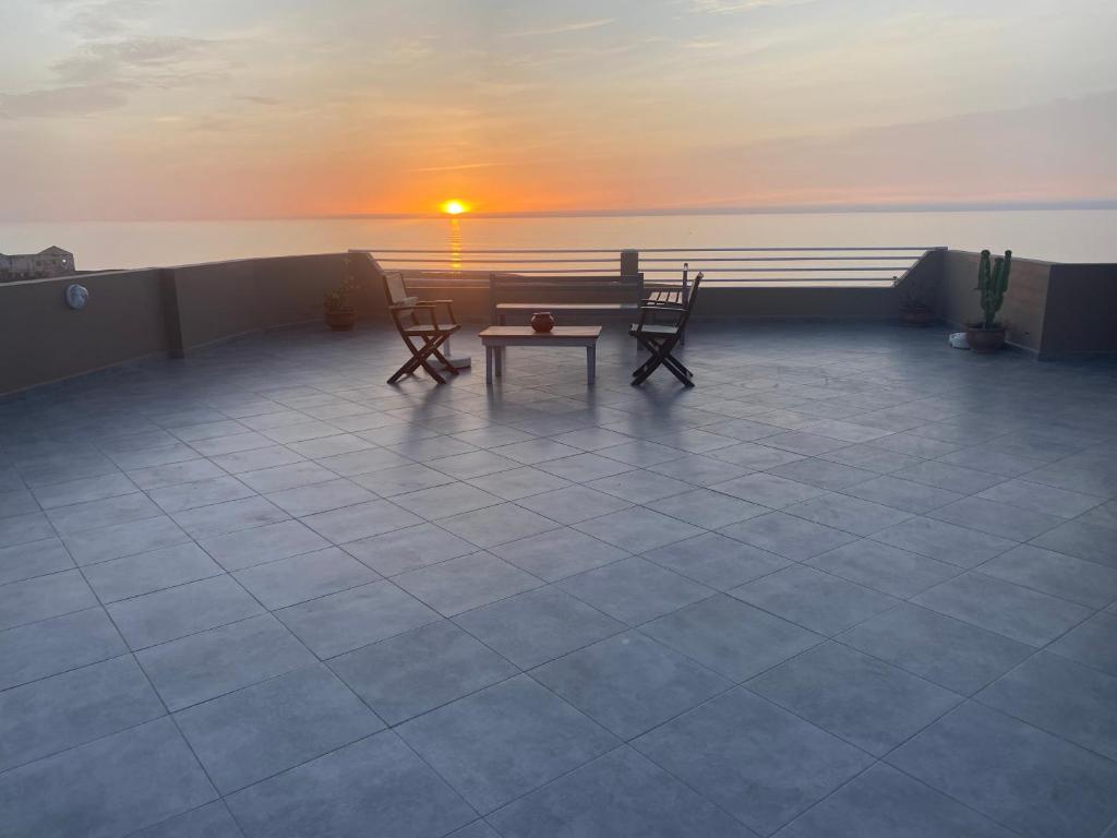 d'une terrasse avec une table et des chaises et le coucher du soleil. dans l'établissement Agadir well, à Mirleft