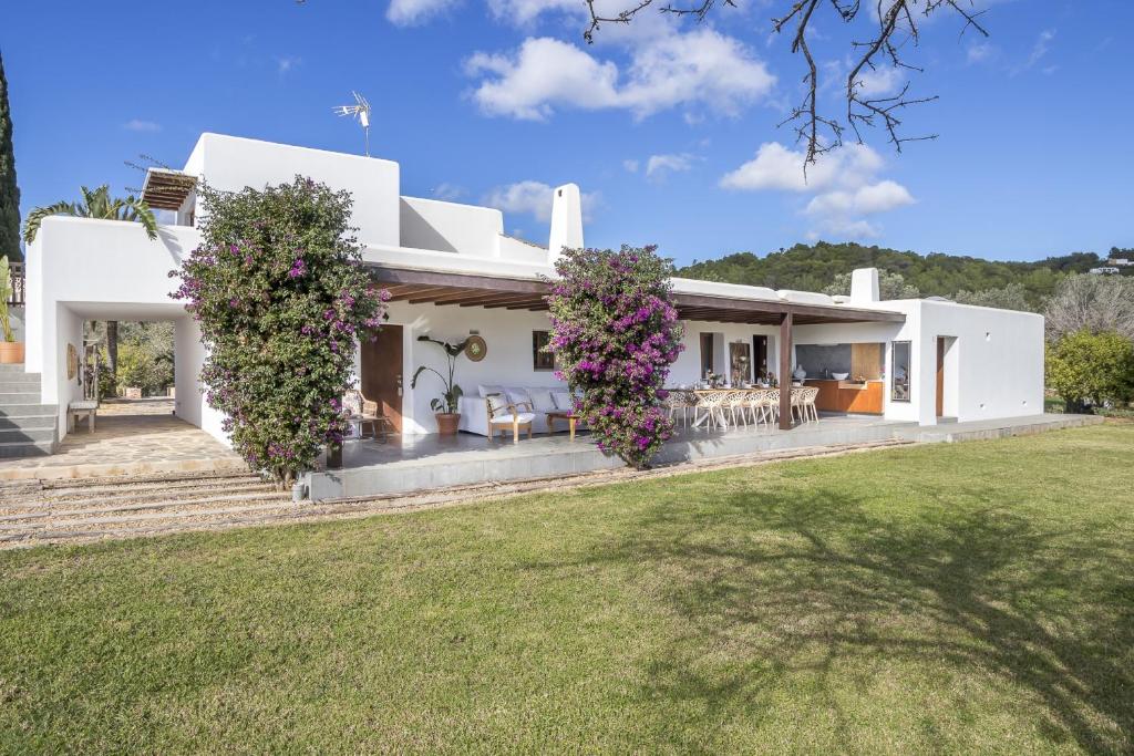 Una casa blanca con flores en la parte delantera. en Ravishing Ibiza Villa Cel Blau 9 Bedrooms Private Pool and Beautiful Country Views Santa Eulalia, en Santa Eulària des Riu