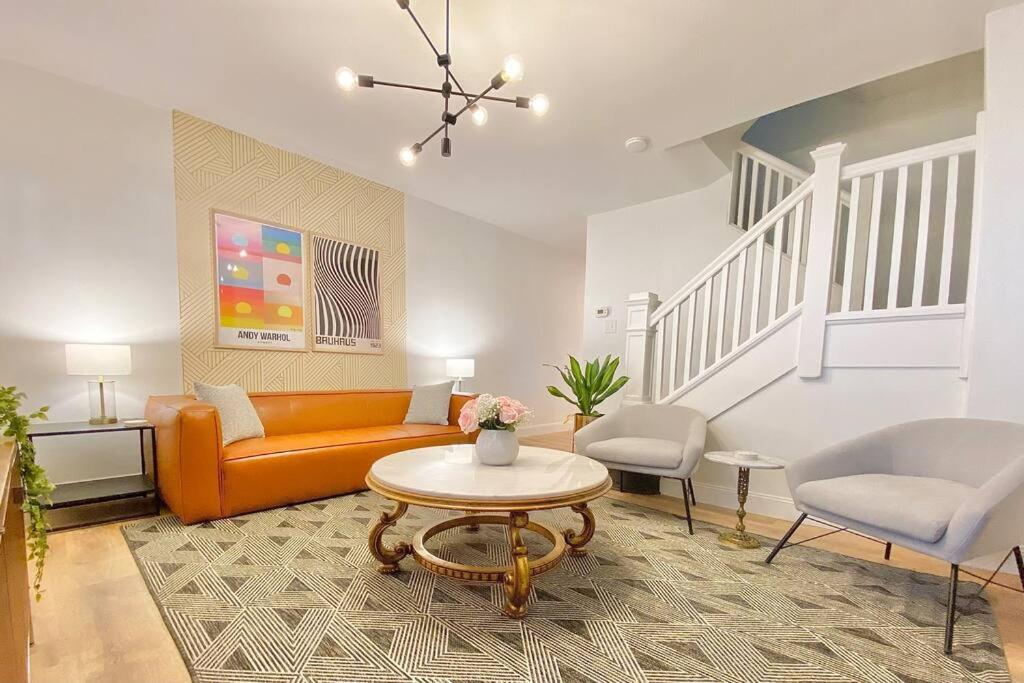 ein Wohnzimmer mit einem orangenen Sofa und einem Tisch in der Unterkunft The Kaufman Bakery Square by Luxe PGH in Pittsburgh