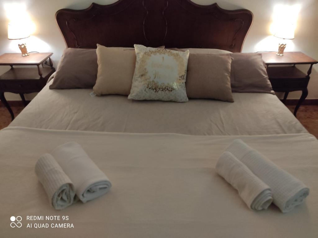 ein Bett mit drei Kissen darauf und zwei Tischen in der Unterkunft Holiday house I Colli Pisani in Capannoli