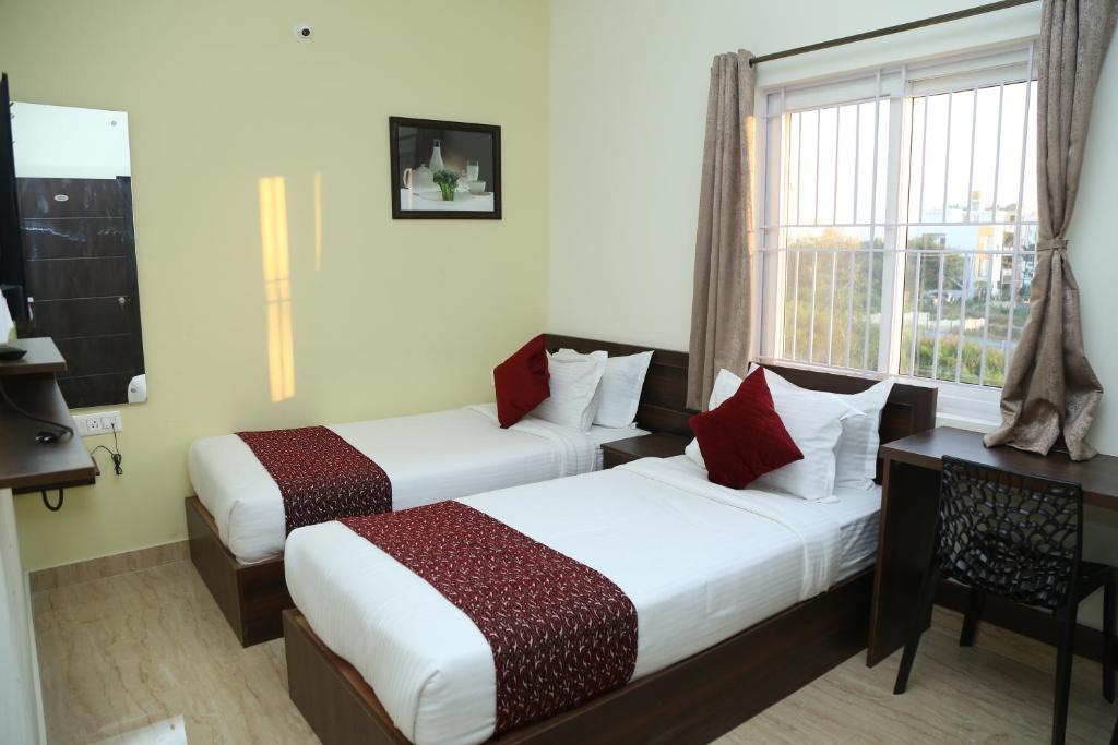 a hotel room with two beds and a window at Bangalore Airport Inn Hotel, Near Kempegowda Airport in Bangalore