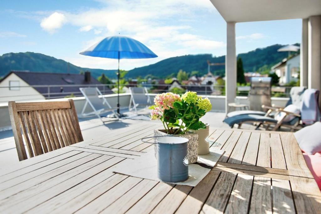 un tavolo in legno con fiori e un ombrellone su un patio di Bodensee-Apartment SeeZeichen No 26 a Bodman-Ludwigshafen