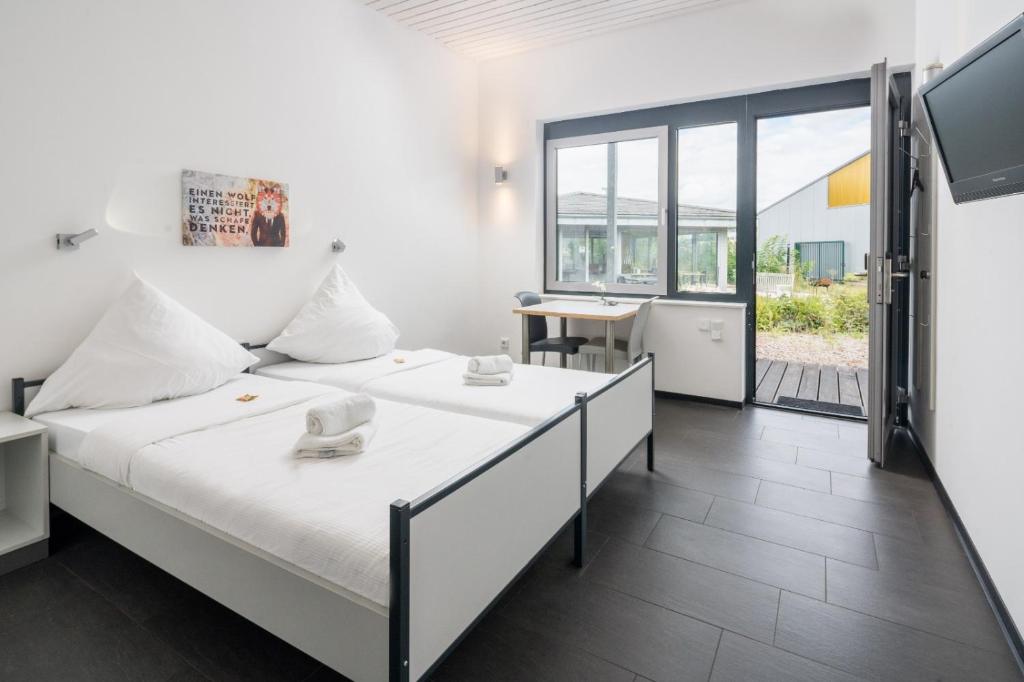 two beds in a room with a large window at Sport Arena Hotel in Waldshut-Tiengen