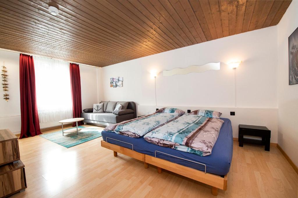 a bedroom with a king sized bed and a couch at Studio Neptun (im Zentrum von Bad Ragaz) in Bad Ragaz