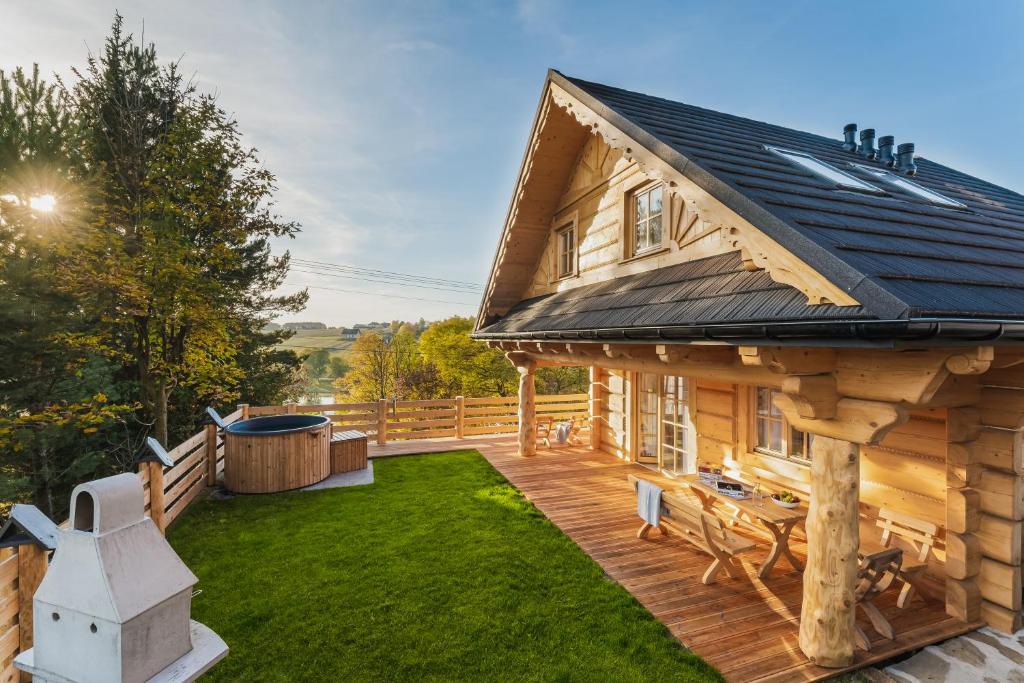 une maison en bois avec une terrasse et une cour dans l'établissement Pienińska Przystań, à Kluszkowce