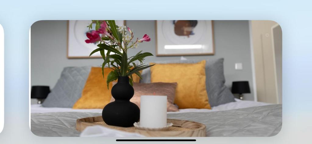 a black vase with flowers on a table with a bed at Hotel Victoria in Dinslaken