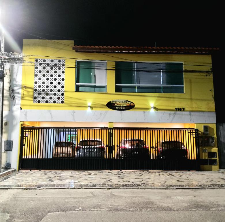 a yellow building with cars parked in front of it at Residencial Sol Nascente in Aracaju
