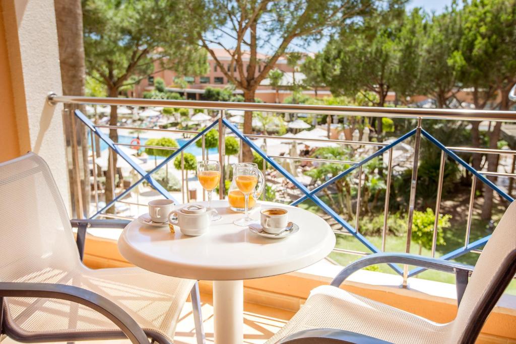 a table on a balcony with two glasses of orange juice at Hipotels Barrosa Garden in Chiclana de la Frontera