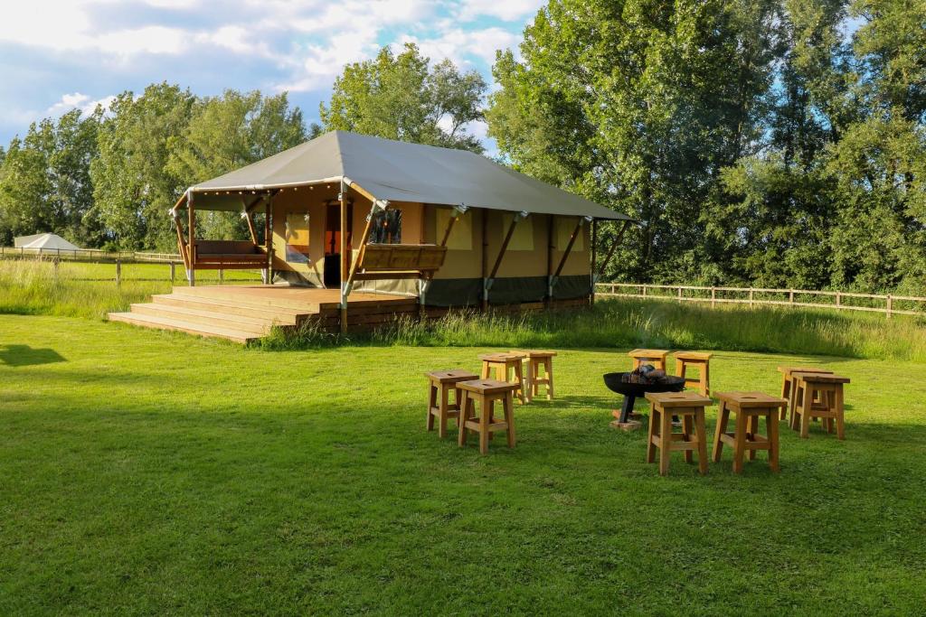 uma tenda com mesas e cadeiras num campo em Horsley Hale Farm Glamping em Ely