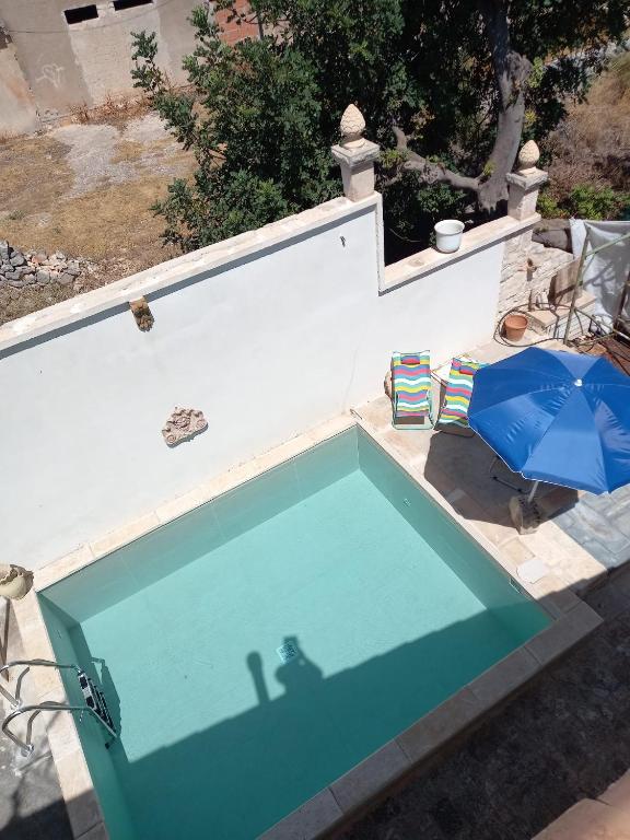 a swimming pool with a blue umbrella and a chair at Casale Oasi in Pozzallo