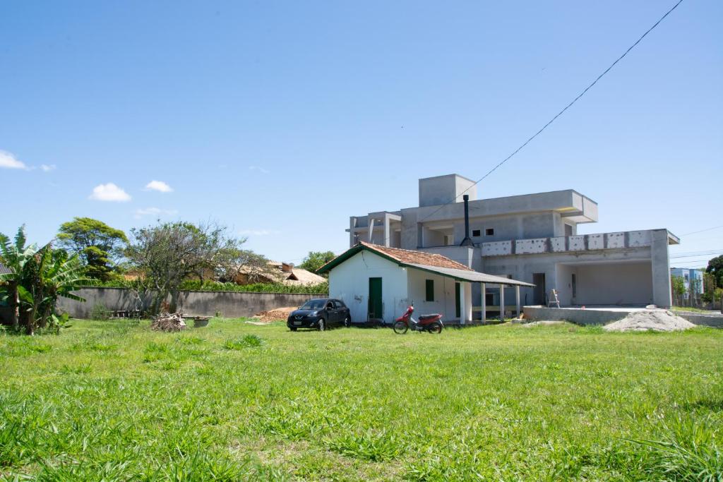 a building with a car parked in a grass field at A Casinha in Florianópolis