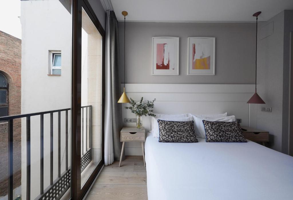 um quarto com uma cama branca e uma varanda em numa I Brio em Barcelona