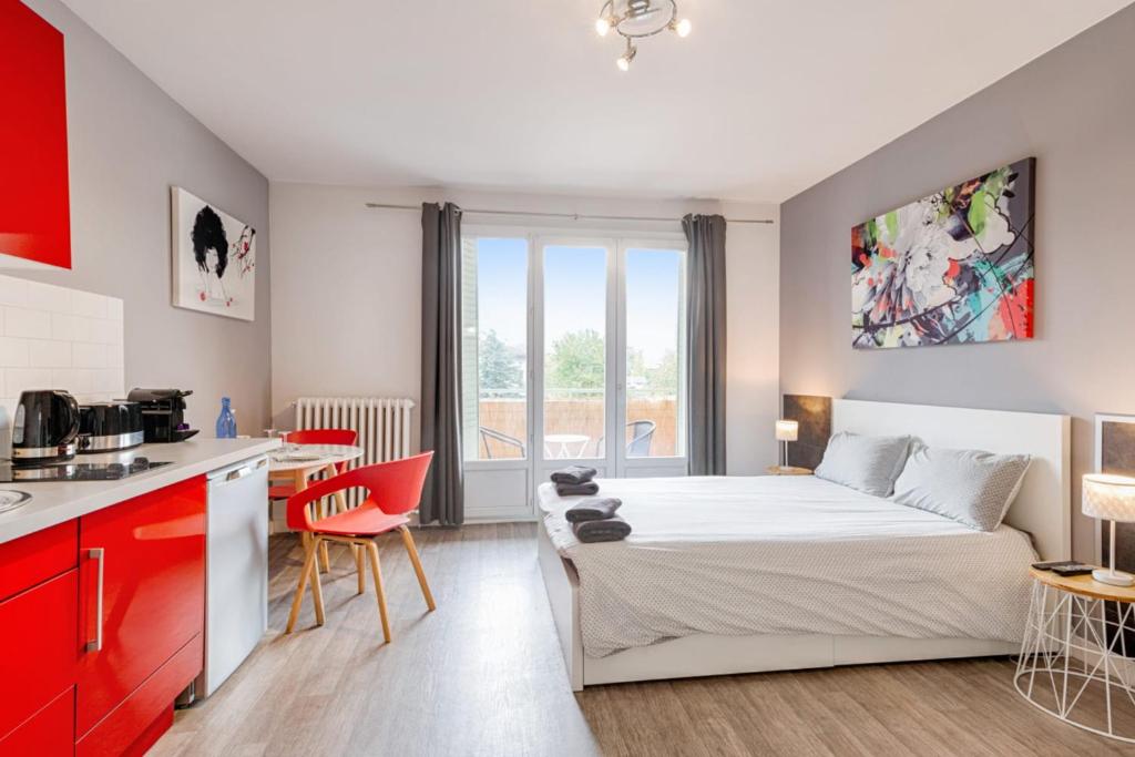 1 dormitorio con 1 cama y cocina con armarios rojos en Annecy Studio balcony close to old town, en Annecy