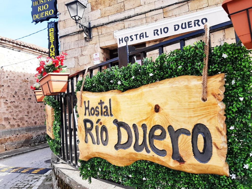 una señal para un rico restaurante colgando de una valla en Hostal Rio Duero, en Molinos de Duero