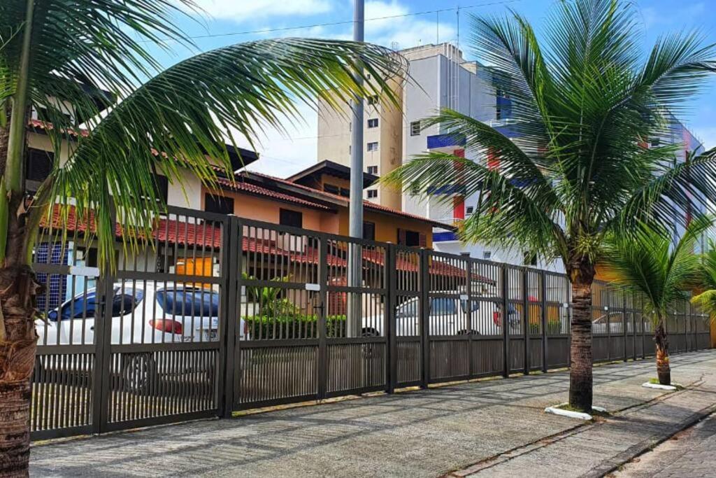 une clôture noire avec des palmiers devant un bâtiment dans l'établissement 100mts DA PRAIA com Churrasqueira, Piscina e Wi-Fi, à Caraguatatuba