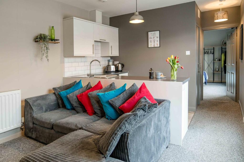 sala de estar con sofá y almohadas coloridas en The Exchange Apartments with Permit Parking, en Tewkesbury
