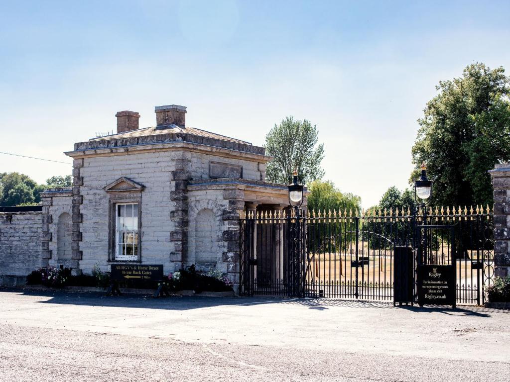 uma velha casa de pedra com um portão preto em Arrow Lodge at Ragley Estate 