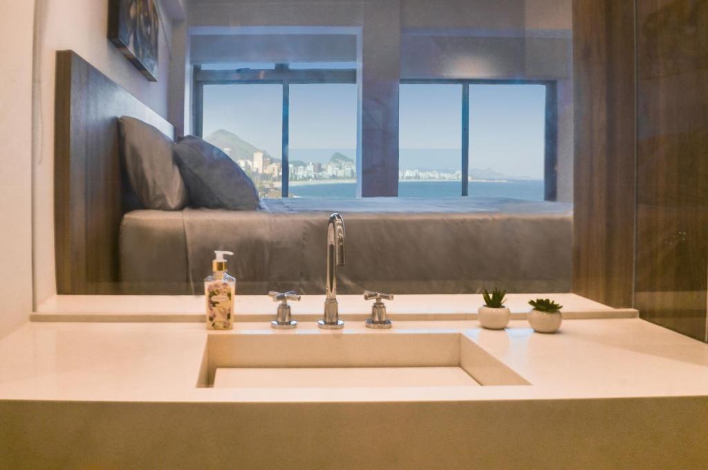 a bathroom sink with a couch in the background at Beach Loft next to the Sheraton Leblon in Rio de Janeiro