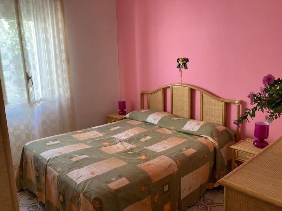 um quarto com uma cama e uma parede rosa em Al Fresco Mare em Triscina