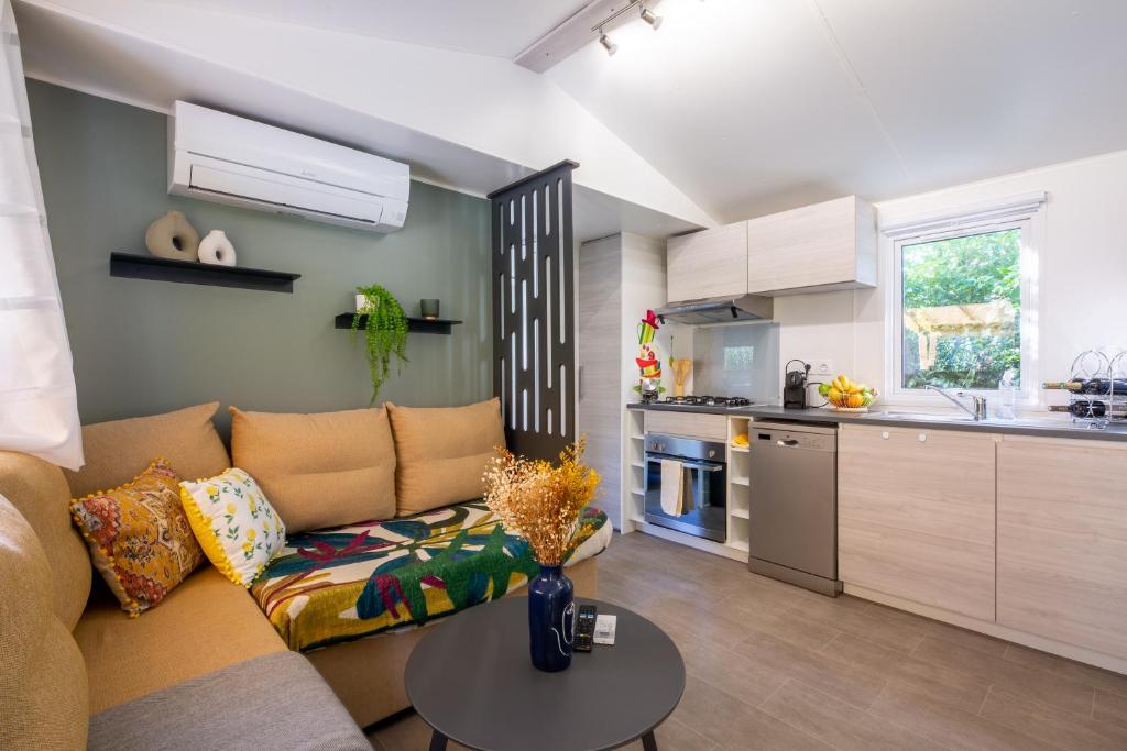 a living room with a couch and a table in a kitchen at Mobil home Queen Margaret in Fréjus