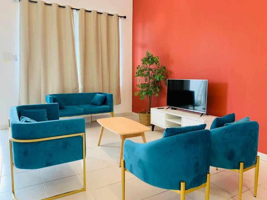 uma sala de estar com cadeiras azuis e uma televisão em Brand New Cozy home Desaru Pengerang near Sebana Cove Resort em Pengerang
