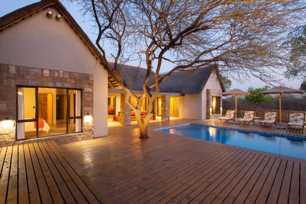 a home with a swimming pool and a house at Vuyani Marula Lodge in Hoedspruit