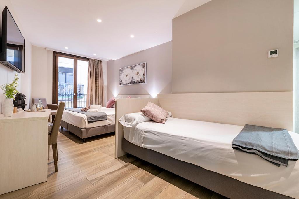 a hotel room with two beds and a desk and a table at Hotel Centre Reus in Reus