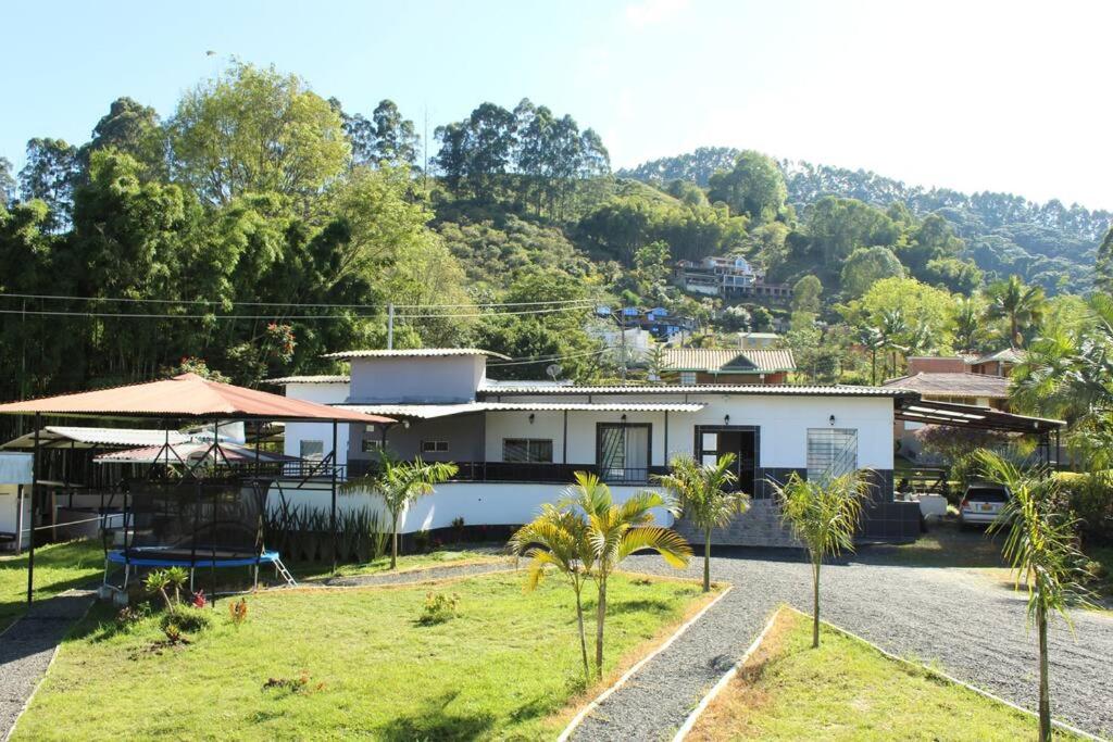 ein weißes Haus mit Bäumen davor in der Unterkunft Villa Natalia Finca, 30 personas, jacuzzi 10 minutos de termales in Santa Rosa de Cabal