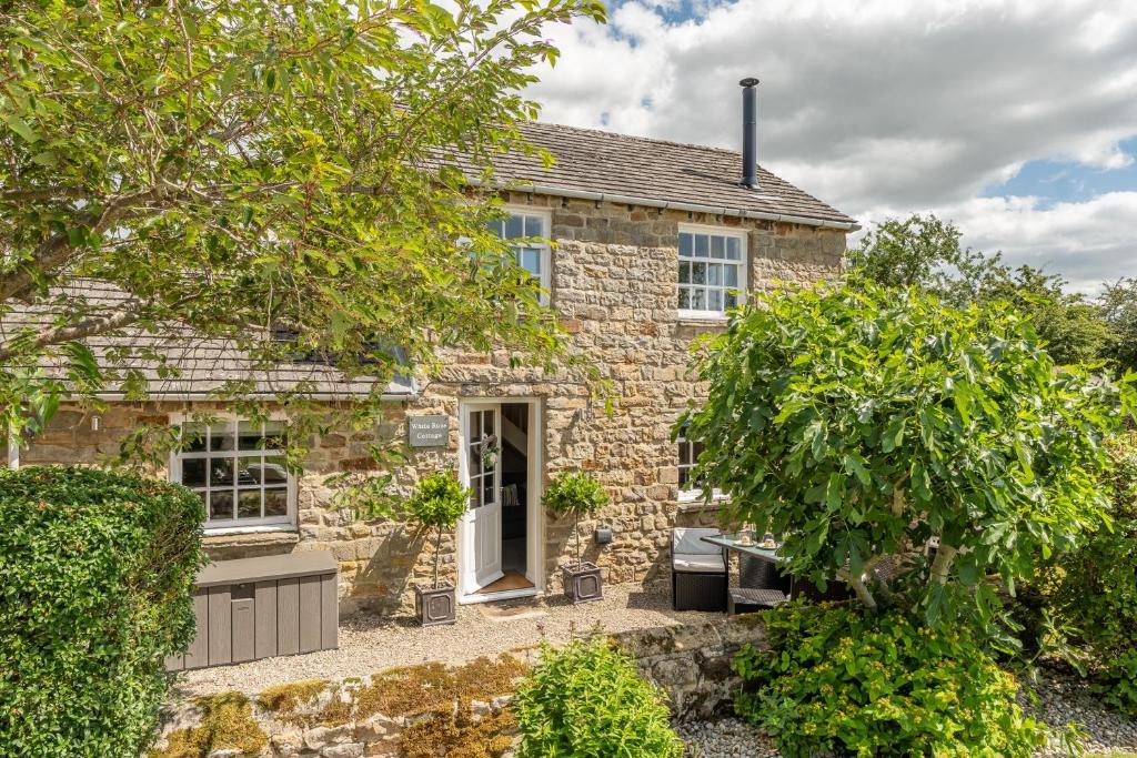 una casa de piedra con un jardín delante de ella en White Rose Cottage, en Constable Burton